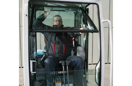 spacious cabin of a takeuchi tb219 with an operator removing the front window