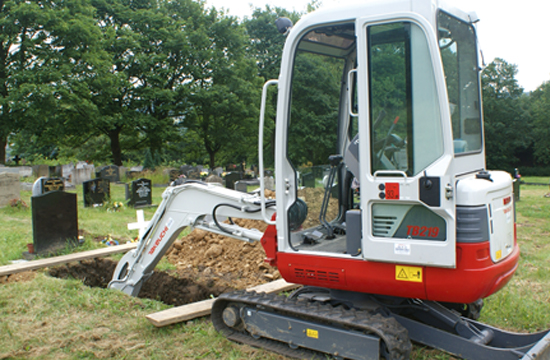 Takeuchi TB219 digger in a graveyard digging a hole