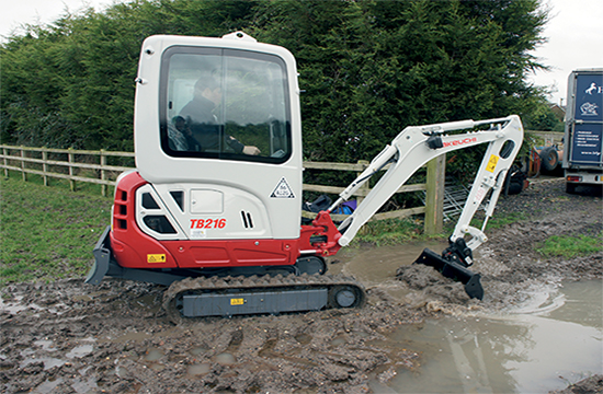 Takeuchi -compact-excavator TB216 digger on a working plant site with bucket attachment machinery down to the floor