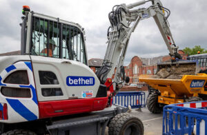 bethell branded takeuchi excavator tipping bucket into a yellow dump truck