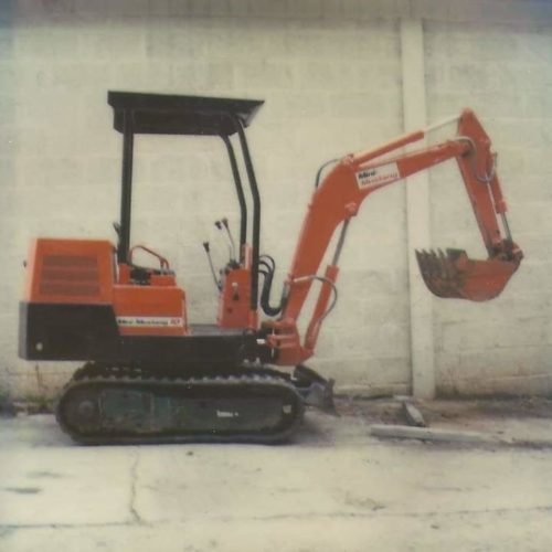 side view of orange takeuchi excavator with mini mustang written on side of machine