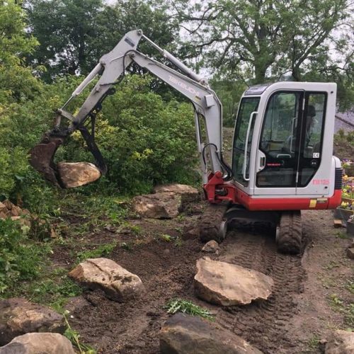 TB125 takeuchi digger picking up a boulder with the excavator on a swivel