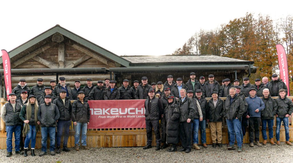 ALl takeuchi staff and dealer network next to logo in front of cabin
