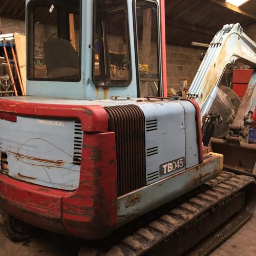 TB045 Takeuchi old working digger painted blue and red in a workshop