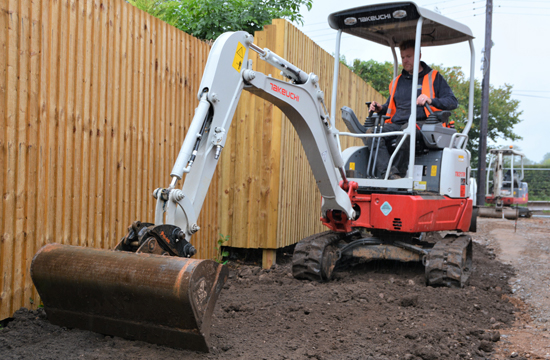 TB217 Compact Excavator with operator driving the digger with boom arm reached out