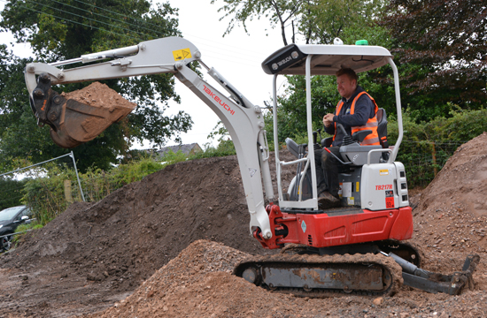 takeuchi tb217r digger with operator showing bucket full of sand and the lifting capabilities of this takeuchi spec