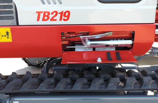 side angle of a takeuchi tb219 excavator with the grease gun panel opened with the gun inside