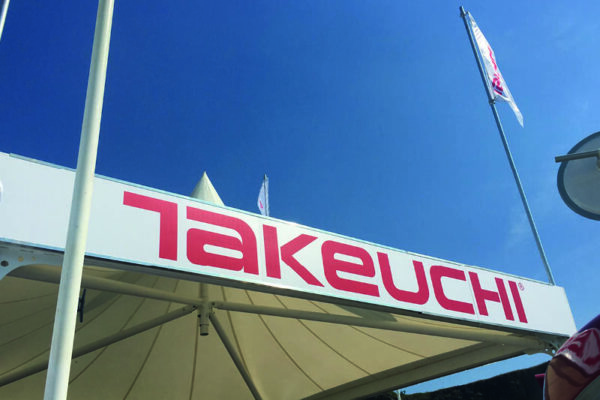 takeuchi logo at top of exhibition with blue sky behind.