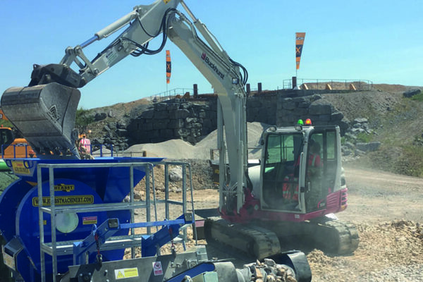 takeuchi digger pouring into materials machine