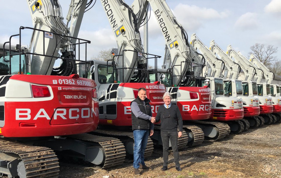 Rob Owen shaking hands with a customers in front of lots of large takeuchi diggers that have been branded up