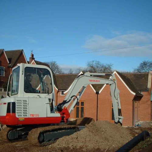 Takeuchi TB135 digger on a new house building constuction site with blue sky