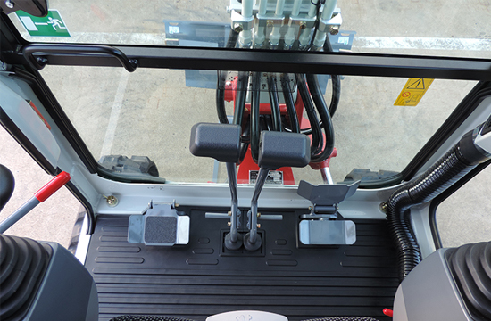 takeuchi TB216 view from operator cabin seat inside the digger facing down showing where your feet would go with pedals and controls view a view of boom machinery outside the front
